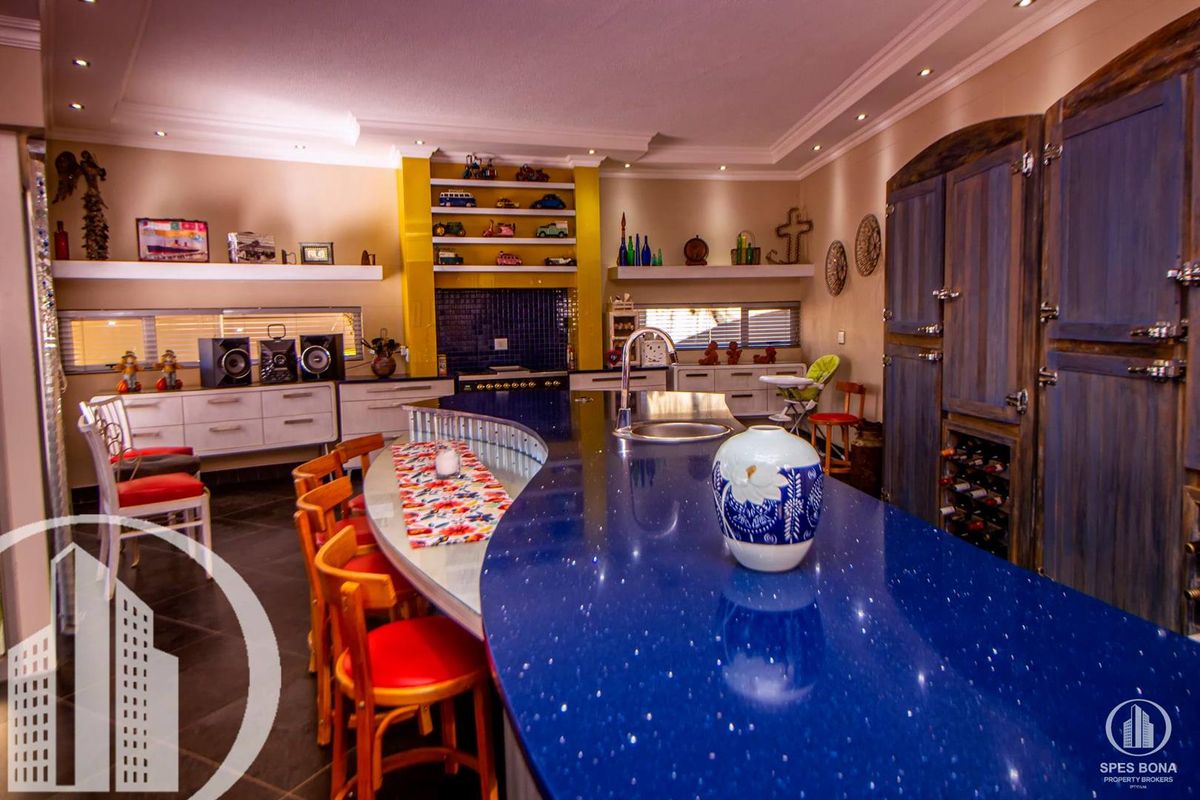 Spacious kitchen featuring a large blue quartz island, built-in cabinetry, recessed lighting, and tiled flooring.