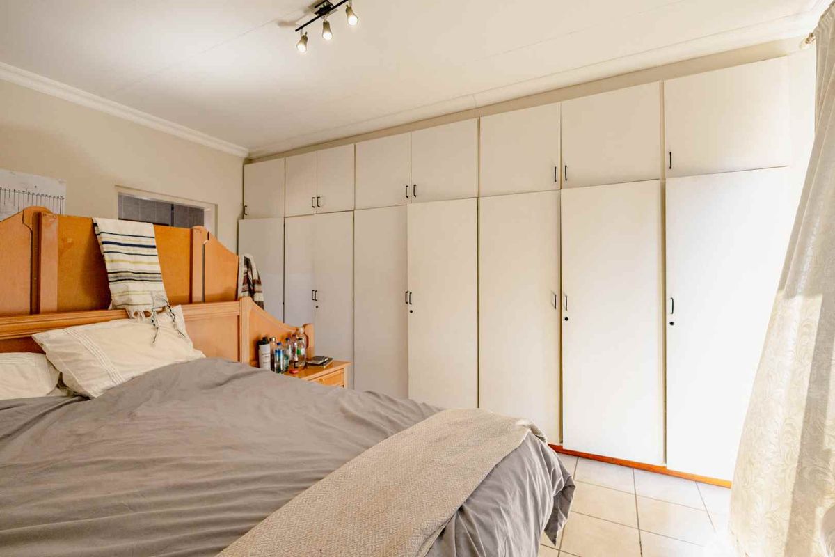A bedroom featuring extensive floor-to-ceiling built-in cupboards and tiled flooring, providing ample storage space.