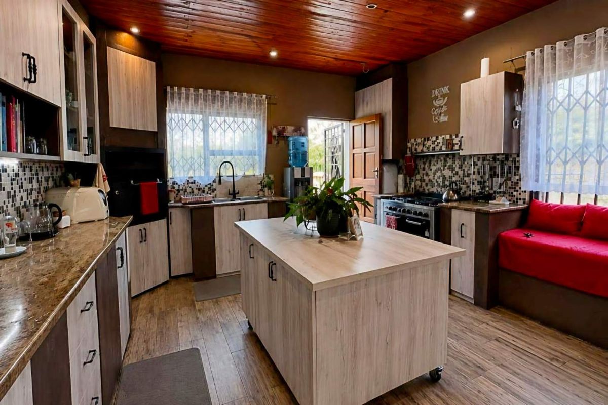 Spacious kitchen featuring timber ceilings, granite countertops, a central island, mosaic tile backsplash, and ample cabinetry with integrated gas stove and extractor fan.