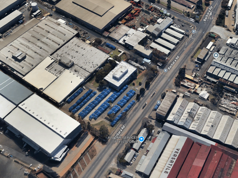 Aerial view of an industrial property complex featuring large warehouse structures, paved yard areas, and street-level access.