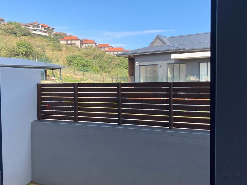 A view from the property looking out towards neighbouring residential buildings, featuring a timber slat privacy screen and masonry boundary wall.