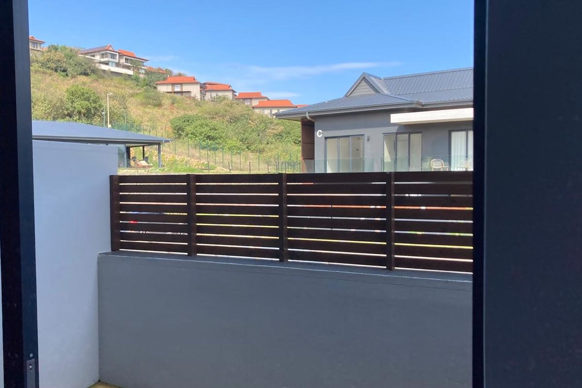 A view from the property looking out towards neighbouring residential buildings, featuring a timber slat privacy screen and masonry boundary wall.