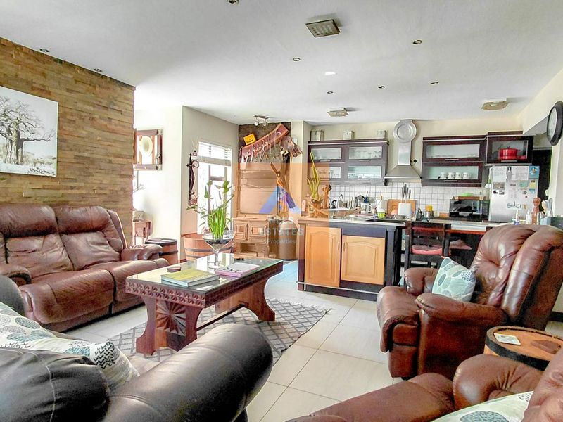 Open plan living and kitchen area featuring a stone accent wall, tiled flooring, and integrated kitchen cabinetry with a stainless steel extractor fan.