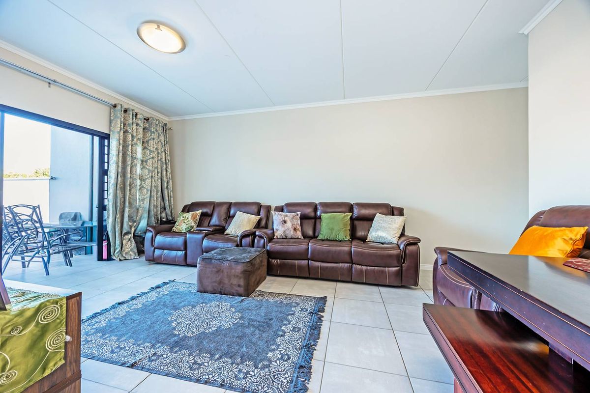 A spacious living room featuring neutral tiled flooring and a large sliding glass door providing access to an outdoor patio area.