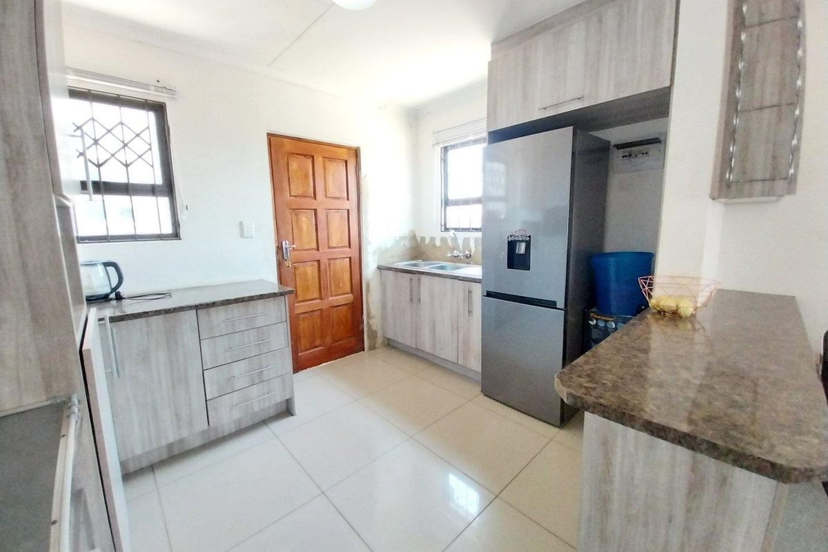 A functional kitchen featuring light wood-grain cabinetry, stone-look laminate countertops, tiled flooring, and security-fitted windows.