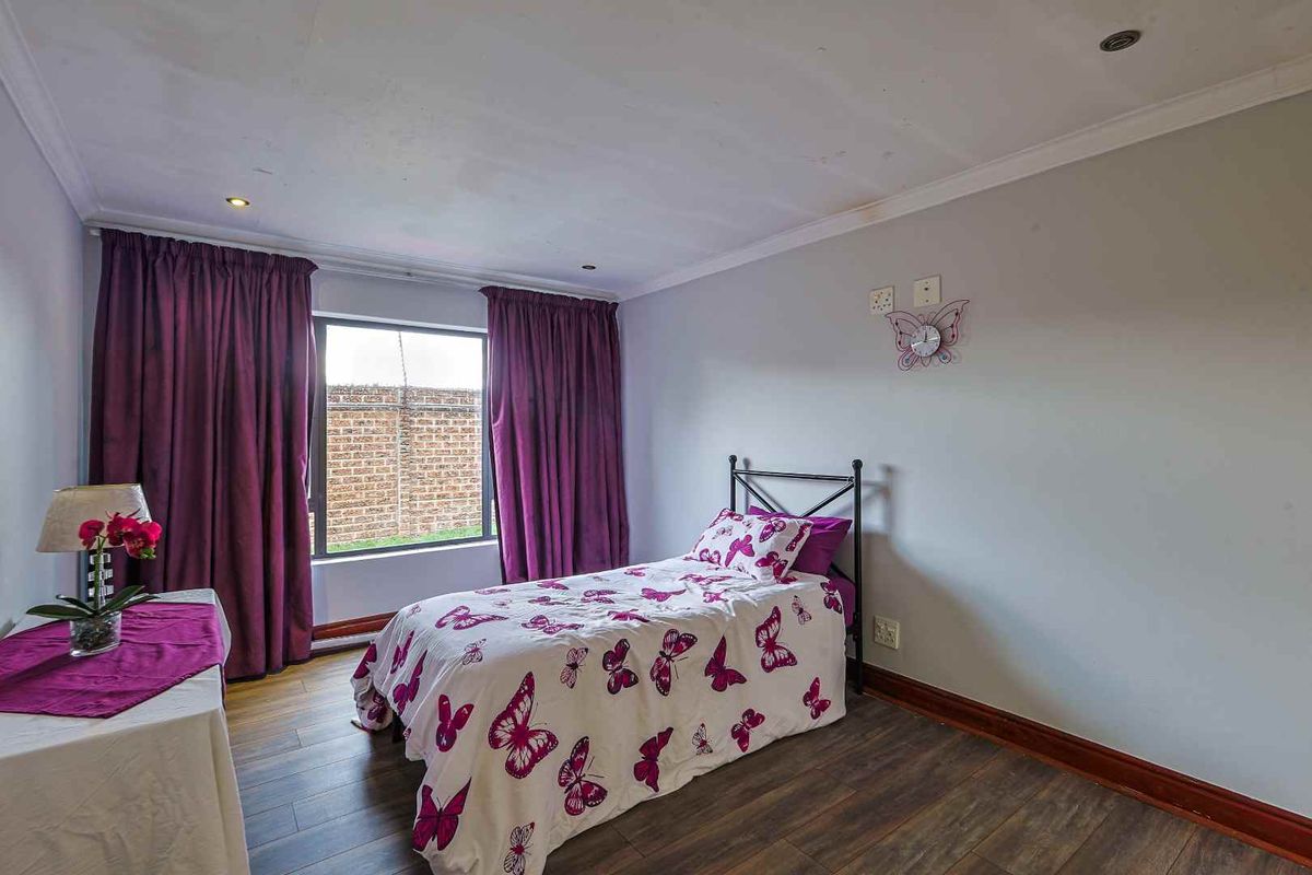 A bedroom featuring laminate flooring and recessed downlights, showing visible signs of ceiling water damage and wear.