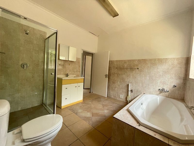 A spacious bathroom featuring a separate shower, built-in bathtub, and vanity unit with neutral wall and floor tiling.