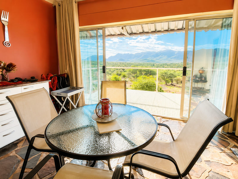 Dining area featuring stone tile flooring, built-in cabinetry, and large sliding glass doors opening to a scenic mountain landscape view.