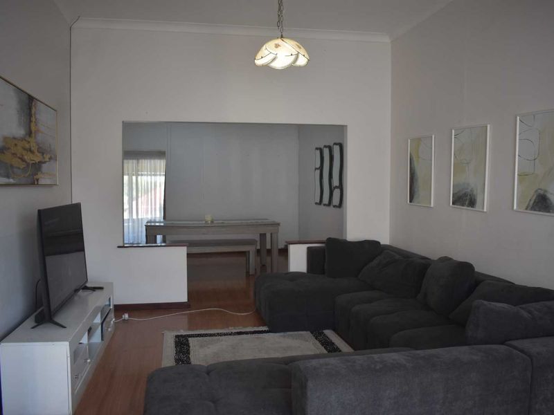 A living room featuring laminate flooring and a pass-through opening to an adjacent dining area, providing an open-plan feel.