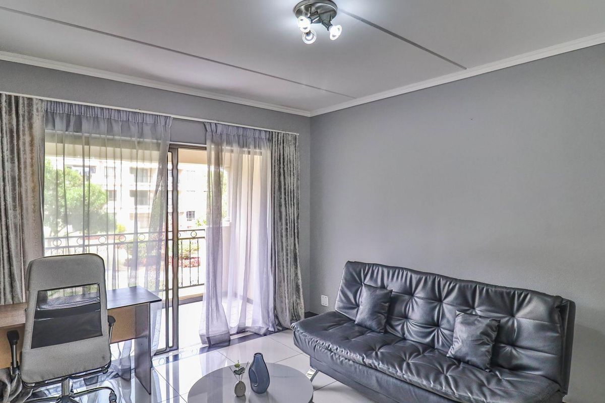 A living room featuring tiled flooring, a ceiling light fixture, and sliding glass doors that provide access to a balcony.