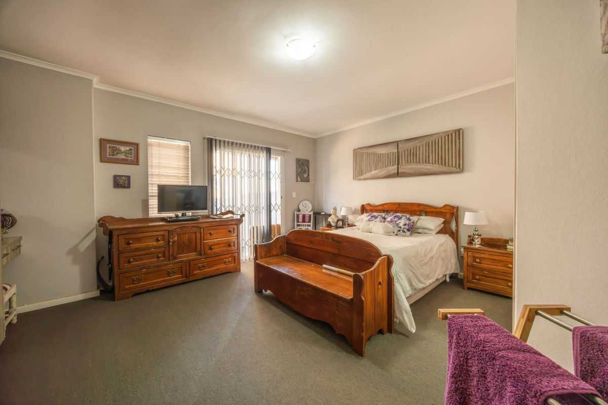 Spacious bedroom featuring neutral wall tones, carpeted flooring, and a sliding glass door providing access to the exterior.