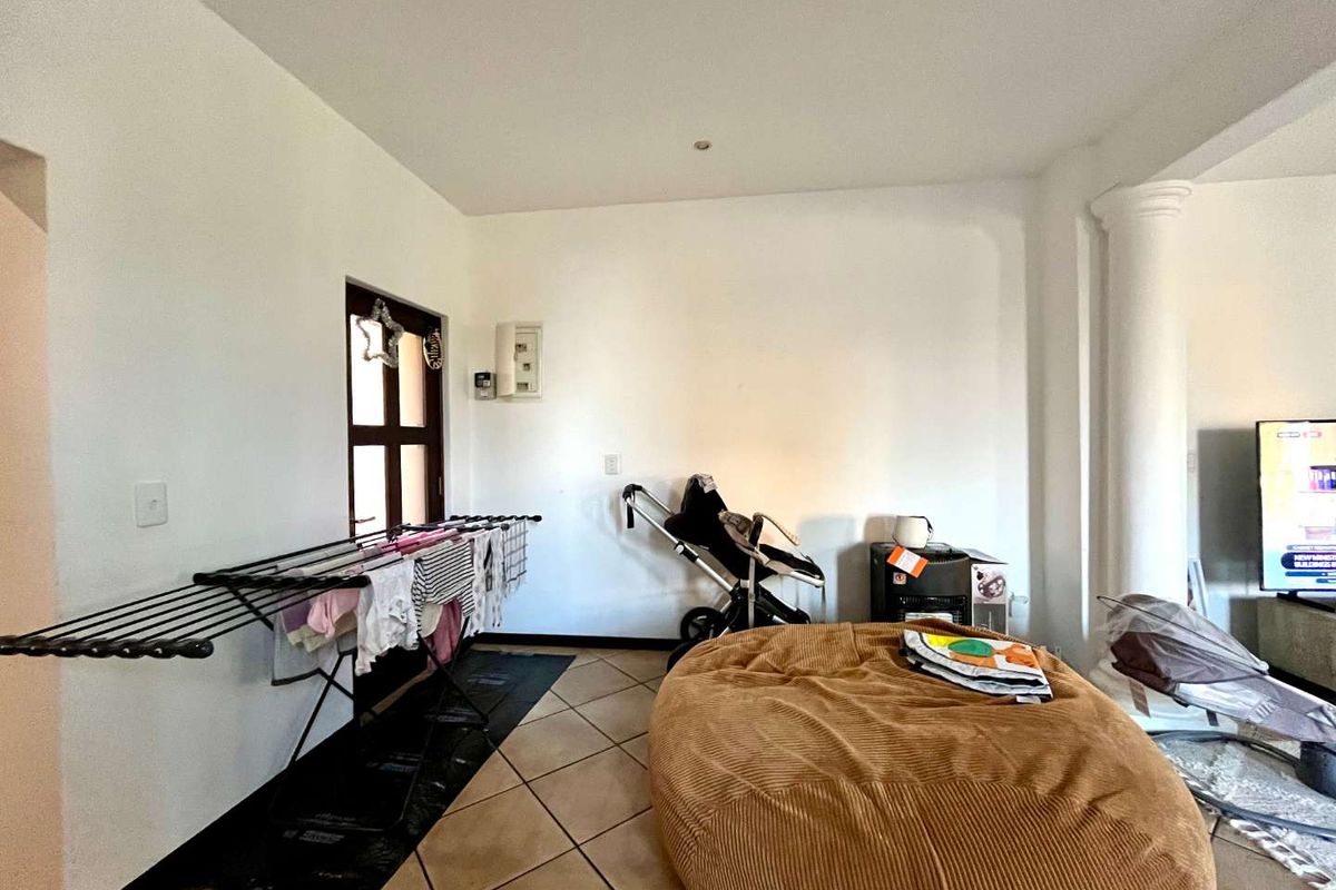 A living area featuring tiled flooring, a decorative column, and access to an exterior door.