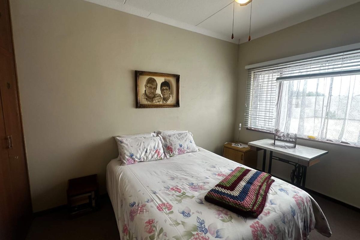 A functional bedroom featuring built-in cabinetry and a window with fitted blinds, providing natural light and storage space.