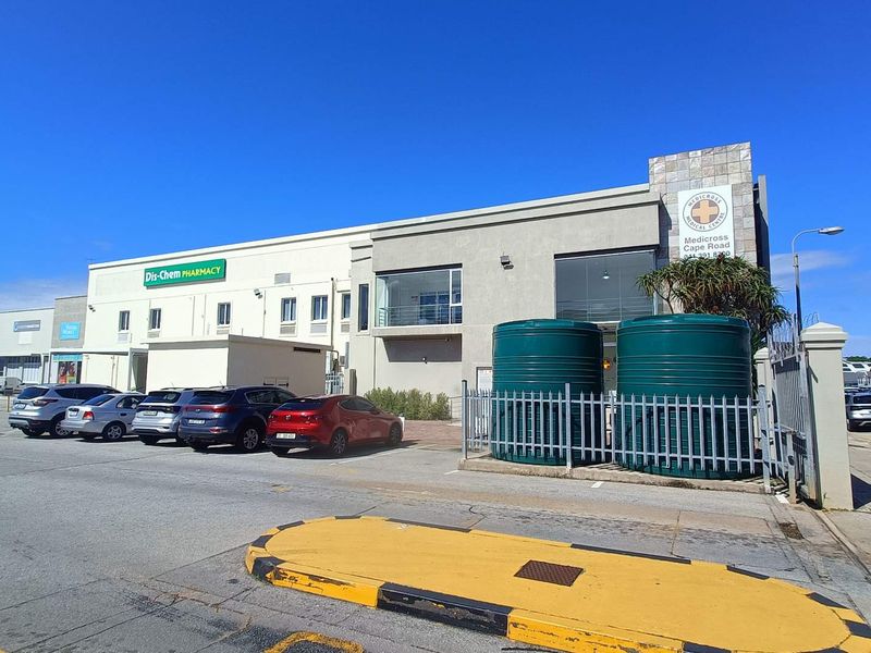 Exterior view of a commercial medical centre building featuring paved parking, prominent signage, and external water storage tanks.