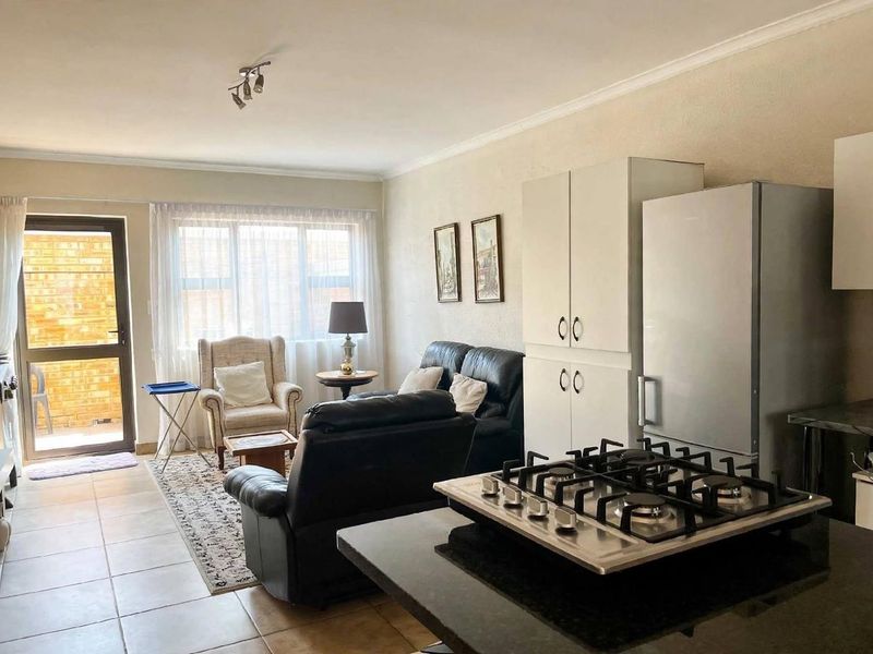 Open-plan living area featuring tiled floors, a functional kitchen with a gas cooktop, and direct access to an outdoor patio area.