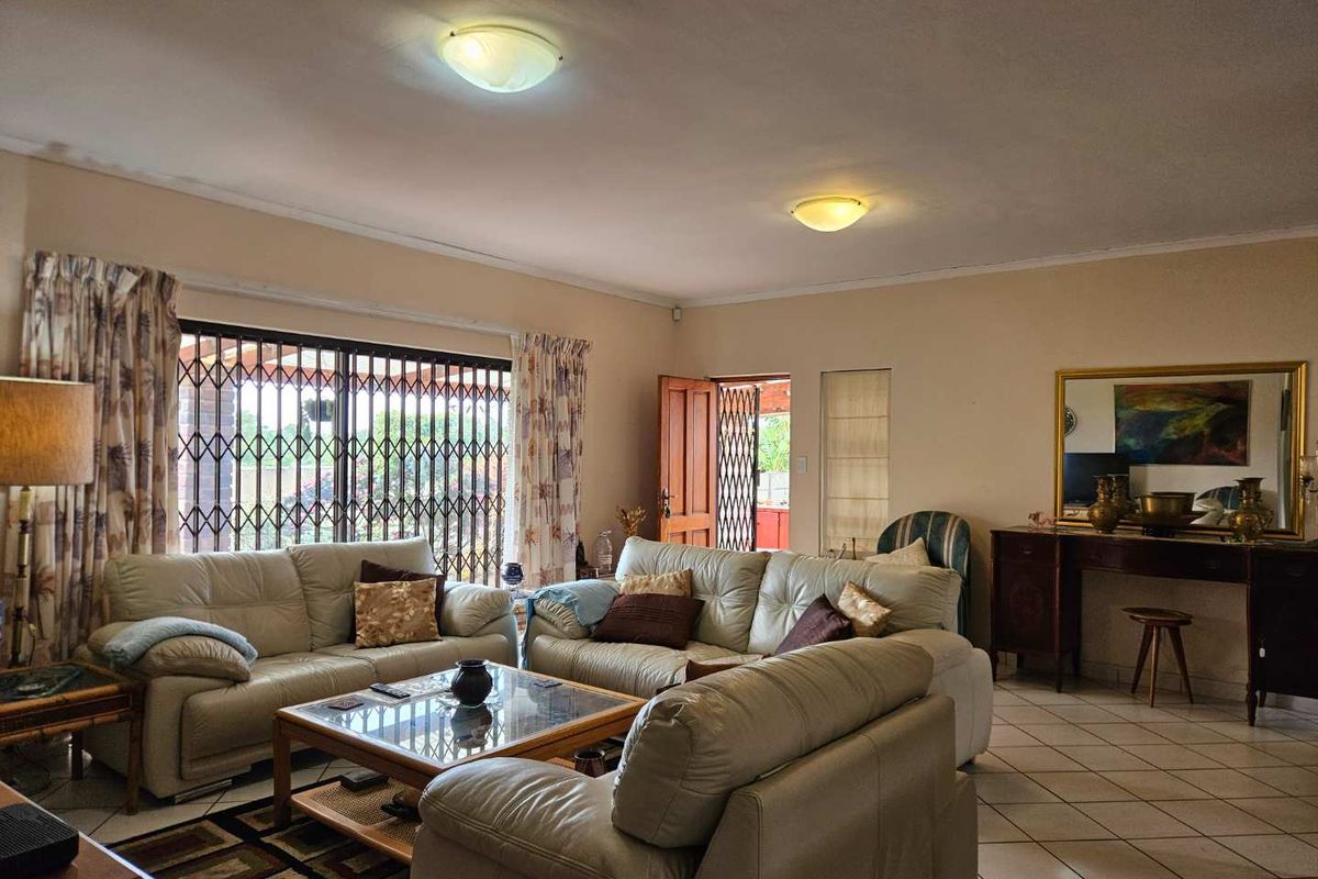 Spacious living room featuring ceramic tile flooring, flush mount lighting, and a sliding glass door with integrated security gate leading to the exterior.