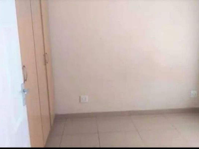 An empty bedroom featuring tiled flooring and built-in cupboards, providing a blank canvas for personalization.