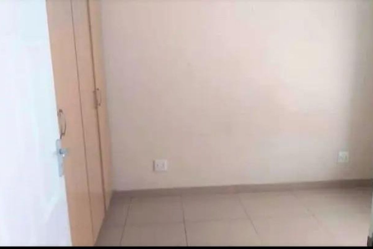 An empty bedroom featuring tiled flooring and built-in cupboards, providing a blank canvas for personalization.