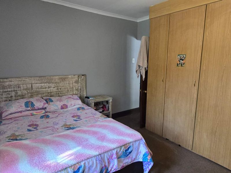 A bedroom featuring built-in wooden cupboards and carpeted flooring, providing functional storage space.