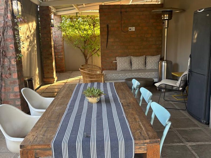 A covered outdoor patio area featuring exposed brick walls, stone flooring, and a dining space, ideal for alfresco entertaining.