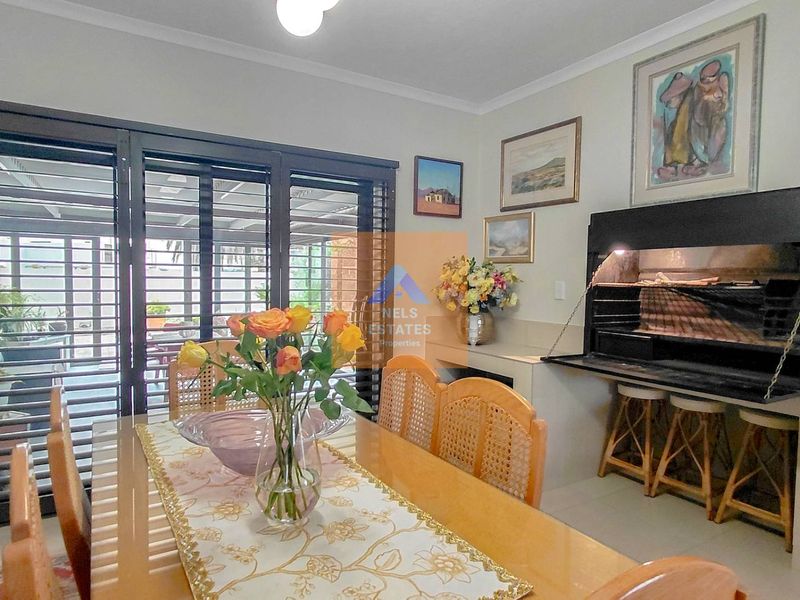 Dining room featuring a built-in indoor braai and large sliding stacker doors providing seamless access to the outdoor patio area.