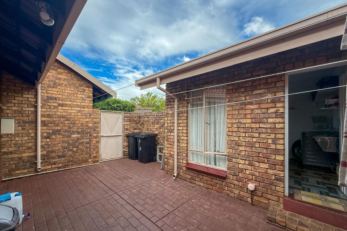 A private rear courtyard featuring brick walls, paved flooring, and access to the laundry area.