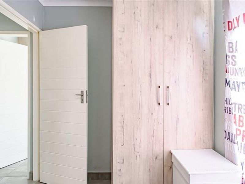 A bedroom interior featuring a light wood-grain built-in wardrobe and a modern horizontal-panel internal door.