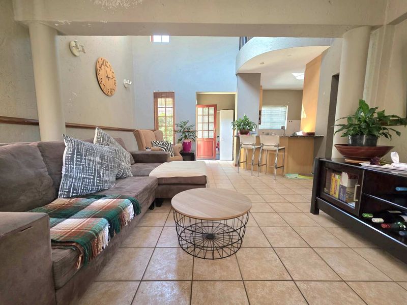 Open-plan living area featuring tiled flooring, a breakfast bar, and double volume ceilings, creating a spacious and connected layout.
