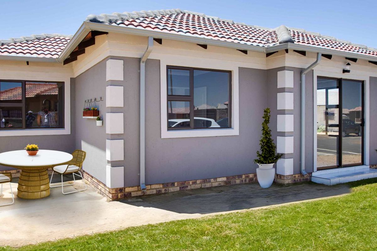 A well-maintained rear exterior view of the house featuring a concrete patio, tiled roof, and modern aluminium window and door frames.