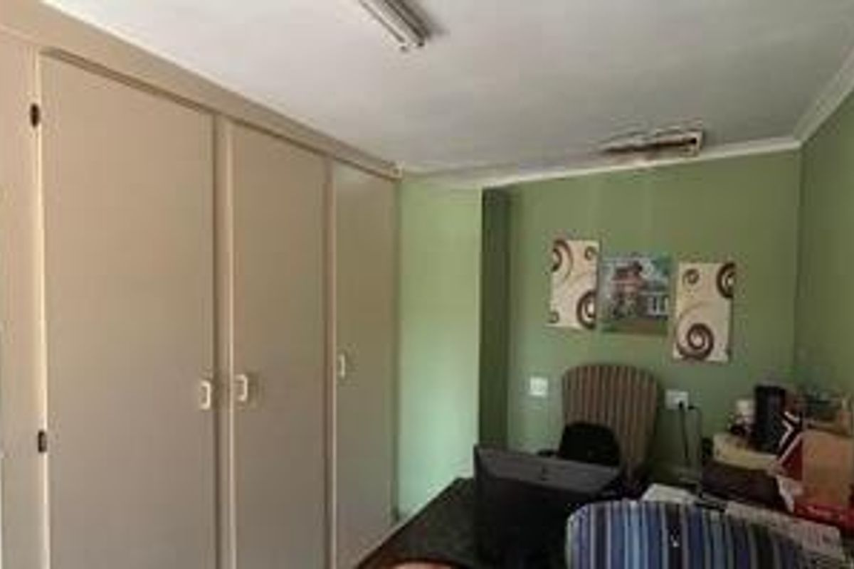 A bedroom featuring built-in cupboards and green painted walls, requiring some cosmetic attention to the ceiling.