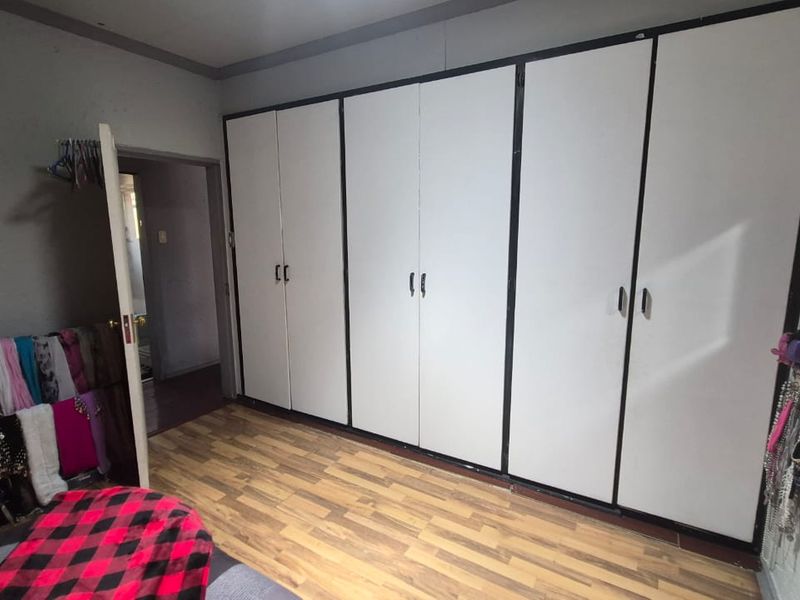 A bedroom featuring extensive built-in cupboards with white doors and dark trim, complemented by wood-look laminate flooring.
