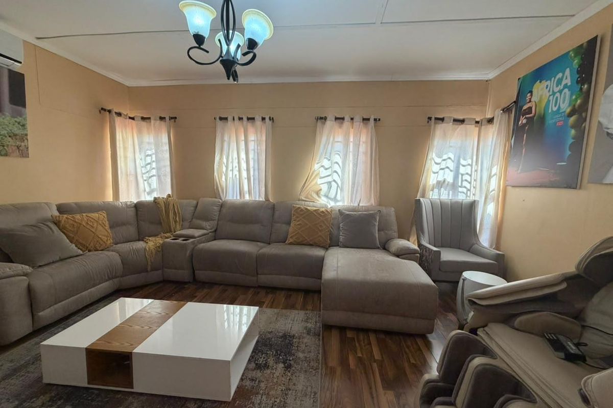 A living room featuring laminate flooring, an air conditioning unit, and a central ceiling light fixture.