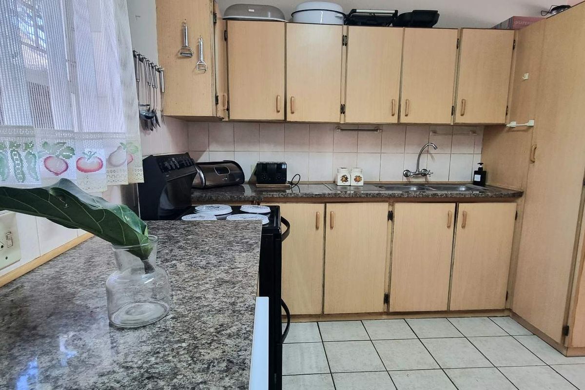 A functional kitchen featuring laminate cabinetry, granite-look countertops, a double sink, and tiled flooring, offering a practical layout for daily meal preparation.
