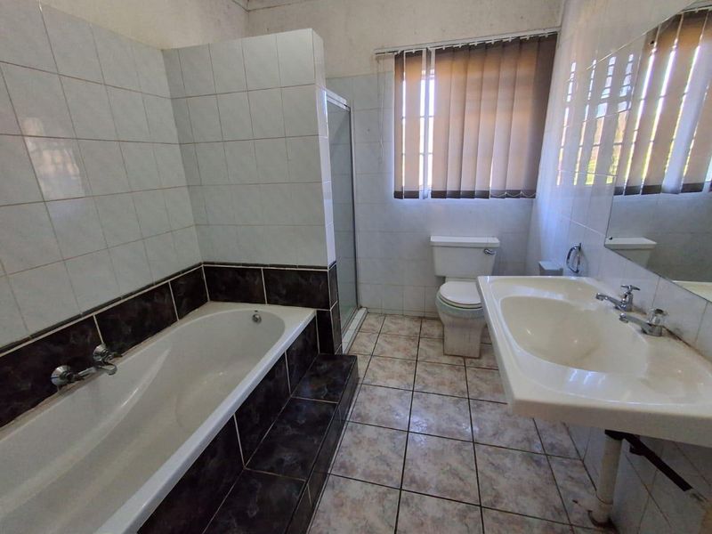 A dated bathroom featuring a built-in bathtub, separate shower enclosure, pedestal basin, and toilet, with tiled finishes throughout.