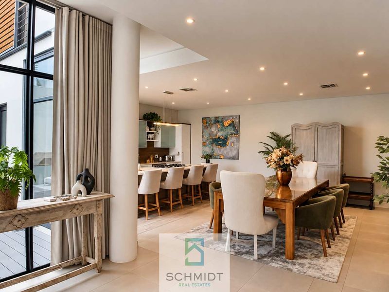 Spacious open-plan living and dining area featuring a modern kitchen with island, recessed lighting, and large floor-to-ceiling windows overlooking the outdoor patio.