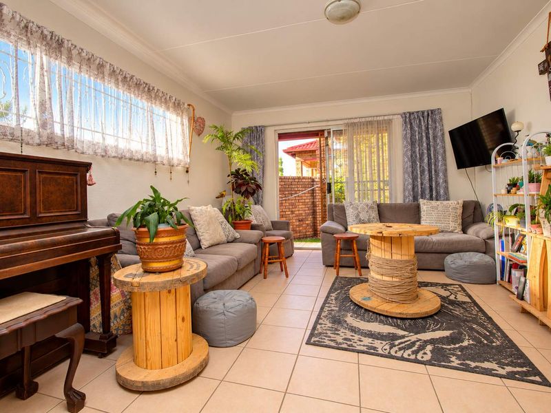 A comfortable living room featuring tiled flooring, a sliding glass door leading to the exterior, and security bars on the windows.