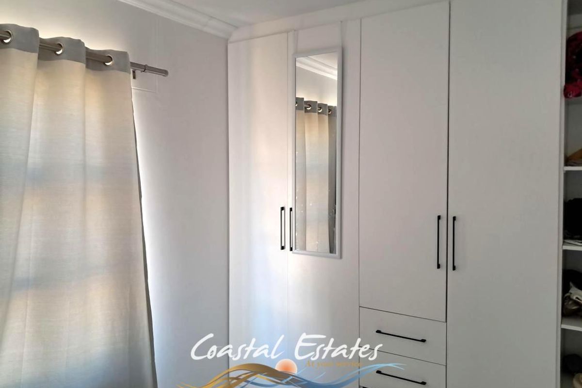 A bedroom featuring built-in white cabinetry with integrated drawers and a mirror, providing ample storage space.