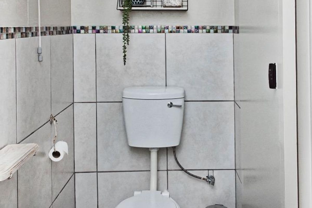 A compact bathroom featuring a standard toilet, tiled walls with a decorative border, and a wall-mounted basin.