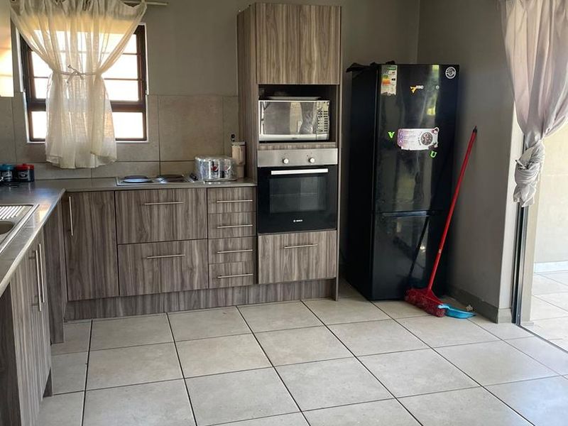 A functional kitchen featuring wood-grain cabinetry, built-in oven and microwave, ceramic tile flooring, and direct access to an outdoor patio area.