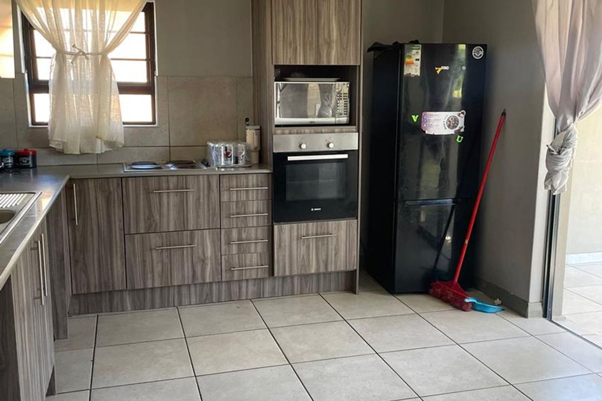 A functional kitchen featuring wood-grain cabinetry, built-in oven and microwave, ceramic tile flooring, and direct access to an outdoor patio area.