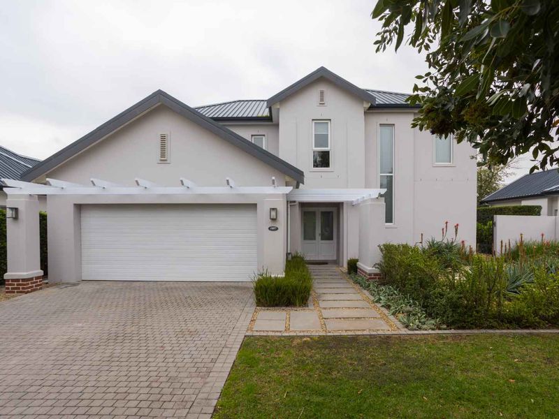 A well-maintained modern double-story home featuring a paved driveway, integrated garage, pergola entrance, and neat landscaped front garden.