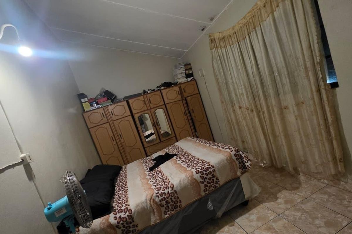 A bedroom featuring tiled flooring and a built-in wardrobe, showing signs of ceiling water damage and wear.