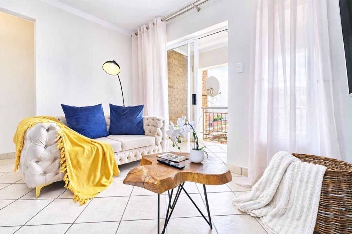 Bright living room featuring tiled flooring and a sliding glass door providing access to an outdoor balcony area.