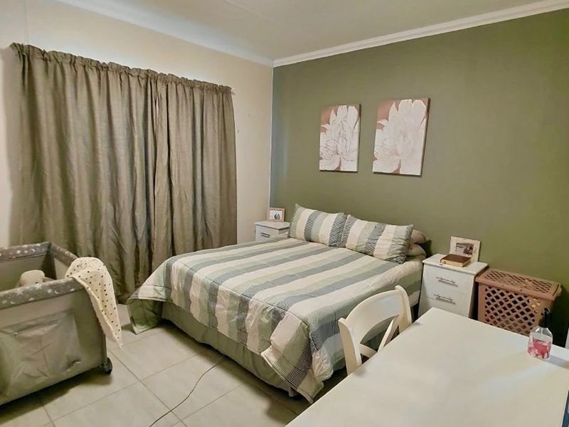 A functional bedroom featuring tiled flooring, neutral wall finishes, and a feature wall, providing a comfortable and practical living space.