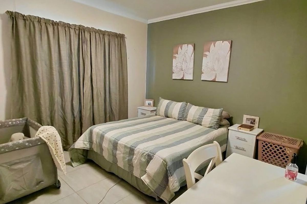 A functional bedroom featuring tiled flooring, neutral wall finishes, and a feature wall, providing a comfortable and practical living space.