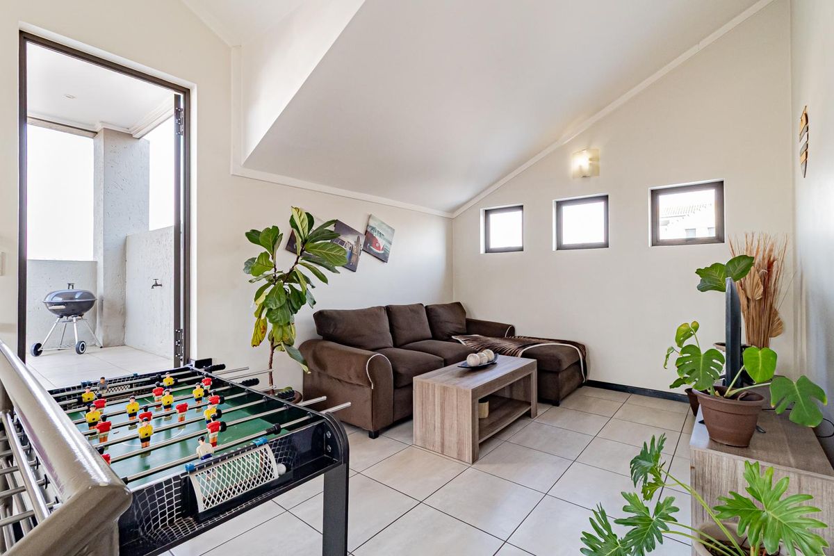 A bright living room with vaulted ceilings, tiled flooring, and direct access to an outdoor patio area.