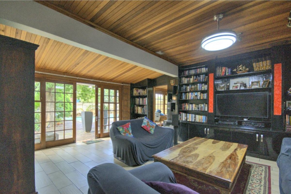 Spacious living room featuring a vaulted timber-clad ceiling, built-in cabinetry, and large glass sliding doors providing direct access to the outdoor patio area.