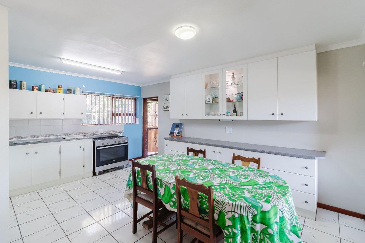 A functional kitchen and dining area featuring white cabinetry, tiled flooring, and a freestanding stove, offering a practical layout for daily meal preparation.