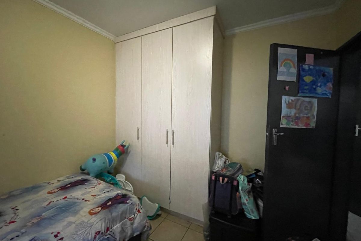 A bedroom featuring a built-in wardrobe, tiled flooring, and neutral wall finishes.