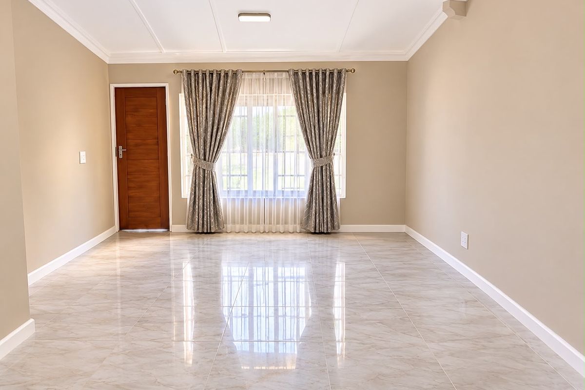A bright, empty living room featuring polished marble-look floor tiles, a coffered ceiling, and a wooden door, offering a clean and modern blank canvas.